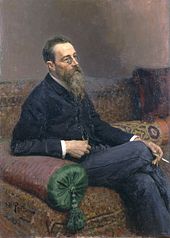 一个戴着眼镜、留着长胡子的男人坐在沙发上抽烟。
