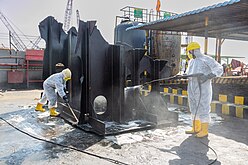 Cleaning of oil-stained sections at Hong Kong Convention-compliant ship recycling yard in Alang, India
