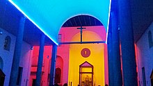 A colorfully lit interior of a church showing the apse and part of the crossing.