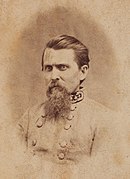Sepia toned photo shows a frowning man with straight combed hair and a frizzy beard. He wears a gray military uniform with a general's stars on the collar.