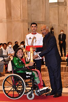 Indian woman in wheelchair receives award from a man who is President