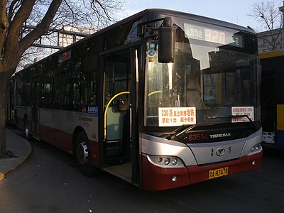 北京公交320路的青年巴士，线路牌混合了显示编号的七段数码管LED电牌和显示目的地的胶牌，此外车头放有宣传该路线的纸牌