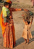 FE5. A young girl in Ahmadabad, helped by mother, prepares to carry the firewood back home. 32.7% of India's population lives on less than the international poverty line of US$ 1.25 per day (PPP) while 68.7% live on less than US$ 2 per day.