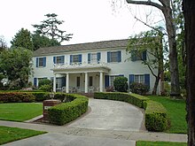 A white house with blue shutters is pictured