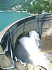 A concrete structure blocking a river discharges water