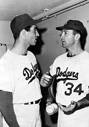 "Two baseball players facing each other and in conversation."