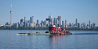 Tugboat pushing a green barge