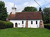 A small, simple, white church, with a red tiled roof and a wooden bellcote