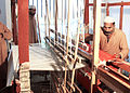 A convicted prisoner trained as a weaver during confinement weaving a red blanket used in Jail Hospitals on a traditional manual loom in 2010.