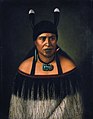 Hinepare, a woman of the Ngāti Kahungunu tribe. She is wearing a pounamu hei-tiki around her neck, and one pounamu earring and one shark tooth earring