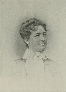 B&W portrait photo of a woman with her hair in an up-do, wearing a pale-colored blouse.