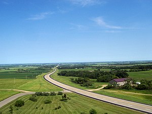 A highway cuts through lush farm fields