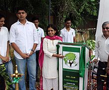 A group of people around Sunita Narain, who is showing a tree logo for the Harithkram eco-club