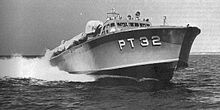 a power boat speeds across the water, riding high so the hullis exposed."PT32"ispaintedonthehullinlargewhiteletters.