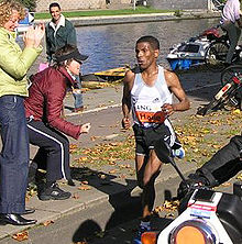 Photo of Haile Gebrselassie running on the street with some bystanders