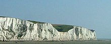 A panoramic photograph of a section of the white cliffs of Dover, with the English channel in front