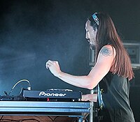 Steve Aoki playing a keyboard while standing against a black backdrop.