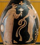 Woman holding a mirror and a tambourine facing a winged genie with a ribbon and a branch with leaves. Ancient Greek red-figure oinochoe, ca. 320 BC, from Magna Graecia. (Notice the coloured decorative woven stripes hanging on the tambourine, which can still be seen today on "tamburello", the tambourine of Southern Italy.)