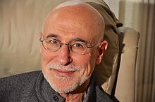 Portrait of Irvin Ungar, from the neck up, facing forward, wearing glasses and smiling slightly.