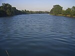 A middle-sized river flows placidly between banks covered in vegetation.