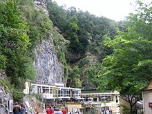 Exposed limestone cliffs with vegetation above white buildings with large windows.