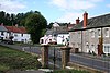 Street scene showing multiple houseson the far side of the road. In the foreground is a metal railing.