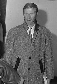 A black-and-white photo of Charlton in a long coat