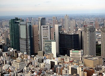 Mid-level view of a city; the tops of trees in the foreground with many high-rise buildings in the background