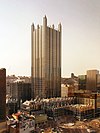 an all glass building with no other tall buildings around it. It is topped off by a glass spire on each corner and is surrounded by much shorter but similarly Gothic glass buildings.