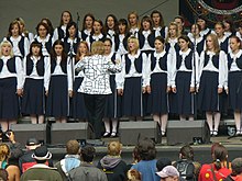 Bambini di Praga choir performing onstage with audience in front, conductor Blanka Kulínská facing the choir