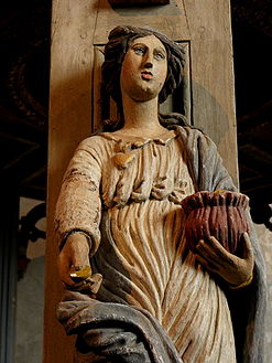 A wood carving, an allegory for "Charity", on one of the five pillars supporting the baldachin.