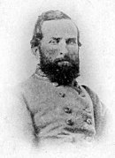 Black and white grainy photo shows a dark bearded man wearing a gray military uniform.
