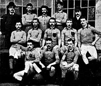 A group of thirteen men, eleven in association football attire typical of the late nineteenth century and two in suits and bowler hats