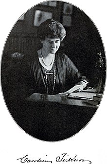 Black and white photograph of Caroline Ticknor. She is seated at a table and looking down at an open book.