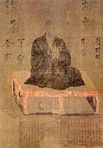 A priest seated on a pedestal in three-quarter view.