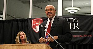 A photo of Williams smiling as he speaks at a University of Denver graduation ceremony held for students in Durango, CO.