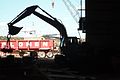 Excavator moving heavy machinery parts with a magnet.