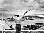 A signalman sends a semaphore message from a Pearl Harbor Control Tower, c. 1960.