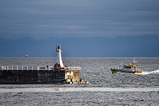 Pilot boat rounding lighthouse at Victoria, Canada and heading out to guide in a ship