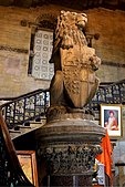 A lion puissant holding the coat of arms of Bombay. In the backdrop is a portrait of Jagannath Shankarseth, one of the founding fathers of the city of Mumbai.