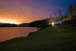 A lake surrounded by trees and fields at sunrise