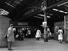 The view inside the vaulted ceiling of a metal shed-like structure, bustling with people