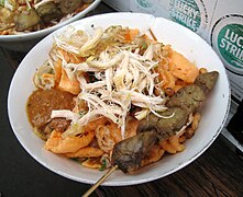 Bubur ayam with chicken liver satay, a popular street food in Indonesia.