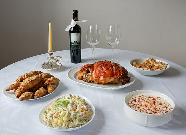 图为塞尔维亚饮食中典型的圣诞菜肴，包括烤猪肉、俄国沙拉、希腊沙律、弗拉纳克红酒、基夫利面包及果馅卷甜点。