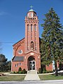 The front of the red-brick St. Joseph's Catholic Church in Egypt, Ohio. The church has a tall bell tower, surmounted by a golden cross.