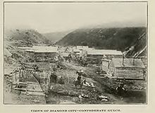 B&W photograph of a street of ramshackle wooden buildings