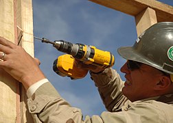 Cordless drill being used to drive screw fastener