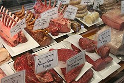 Numerous types of meat on display with labels in a deli