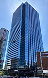 Ground-level view of a glass skyscraper with red accents on its exterior