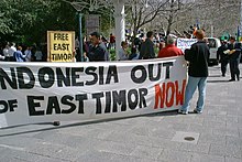 Protestors holding a sign saying "Indonesia out of East Timor NOW"